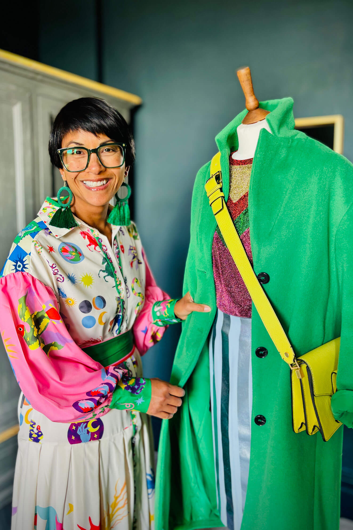 Personal stylist Chantelle Znideric smiles beside a mannequin dressed in a bright green coat and colourful accessories