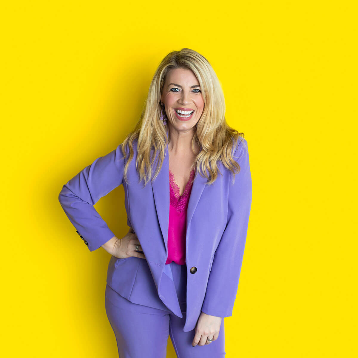 Laura Brunton coach and business mentor laughing confidently in a studio headshot with a bold yellow background