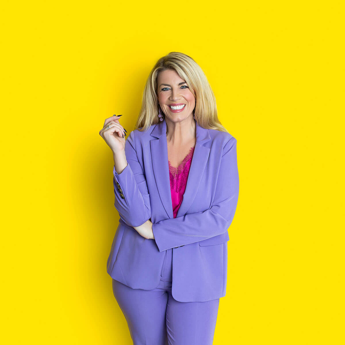 Personal branding headshot of Laura Brunton, business coach, smiling with folded arms in a colourful studio setting