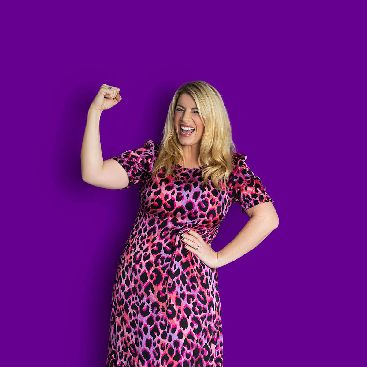 Laura Brunton business coach flexing her arm and smiling confidently against a purple background during a studio branding photoshoot