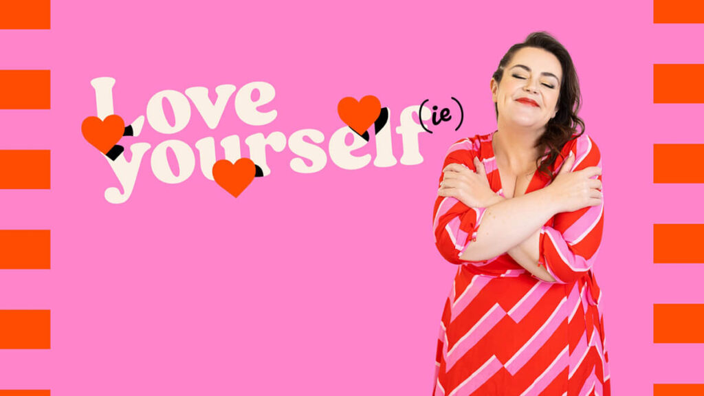 Rosie Parsons, business blogger, smiling with her eyes closed and arms crossed over her chest in a self love hug pose. She wears a red and pink chevron striped dress against a bright pink background with orange stripes. Text reads Love Yourself(ie) with heart graphics. A playful image about practicing self love and self care activities for a healthy lifestyle.