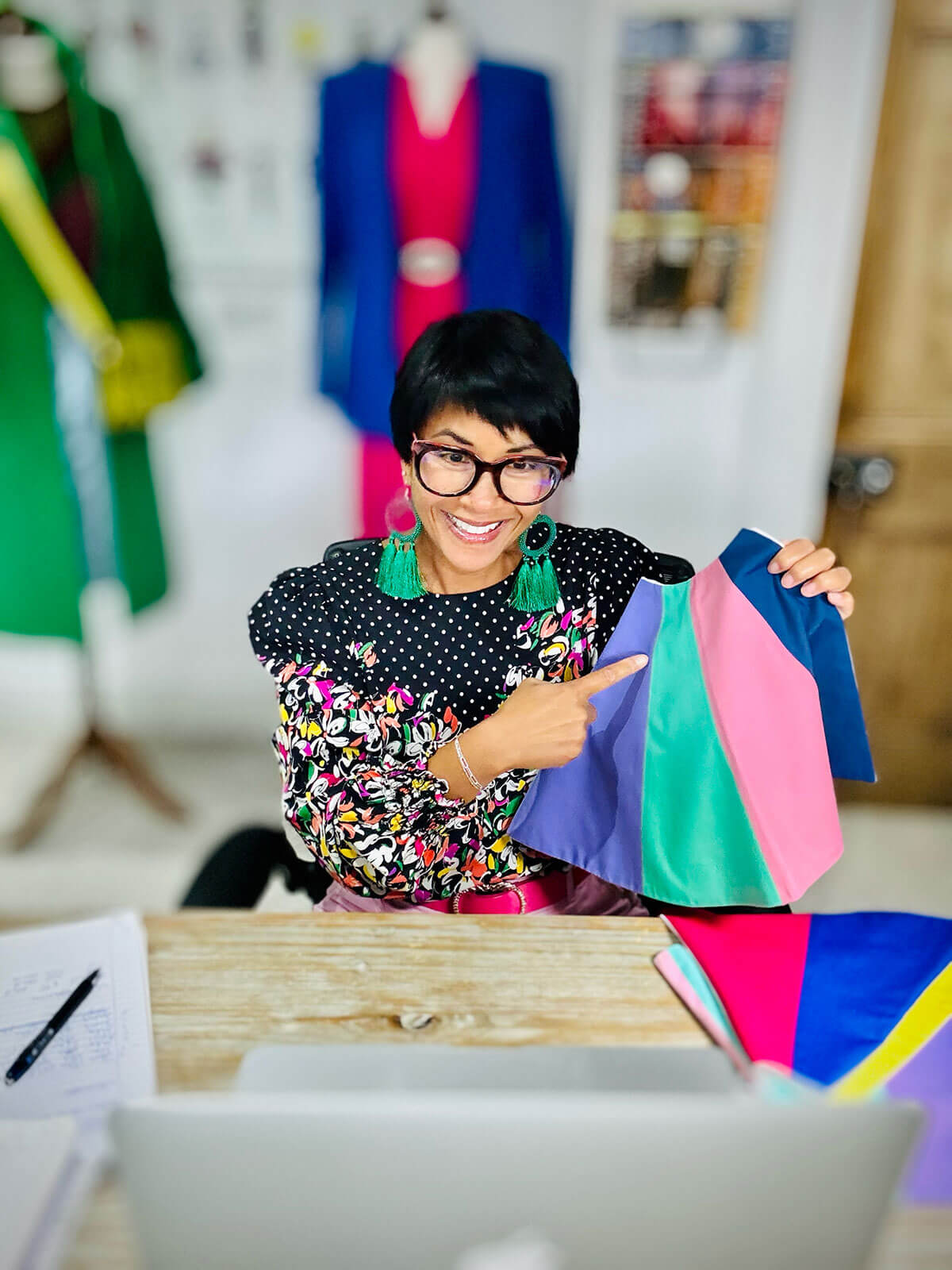 Personal stylist working at her desk with colour swatches, showing personal branding photography for a service-based business. She wears a colorful patterned outfit holding fabric swatches during a fun DIY branding photoshoot in her workspace.